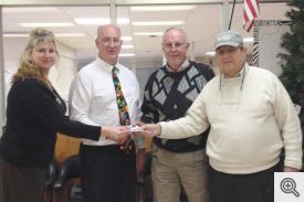 Mountain Pine High School Administrative Assistant Shannon Currington and School Counselor Paul Simms accept a check from Knights of Columbus fundraiser co-chairs Bill Roe and Mike Welsh. 