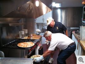 Scott Kantz and Dan Murphy heating the pizzas in the St Francis kitchen.